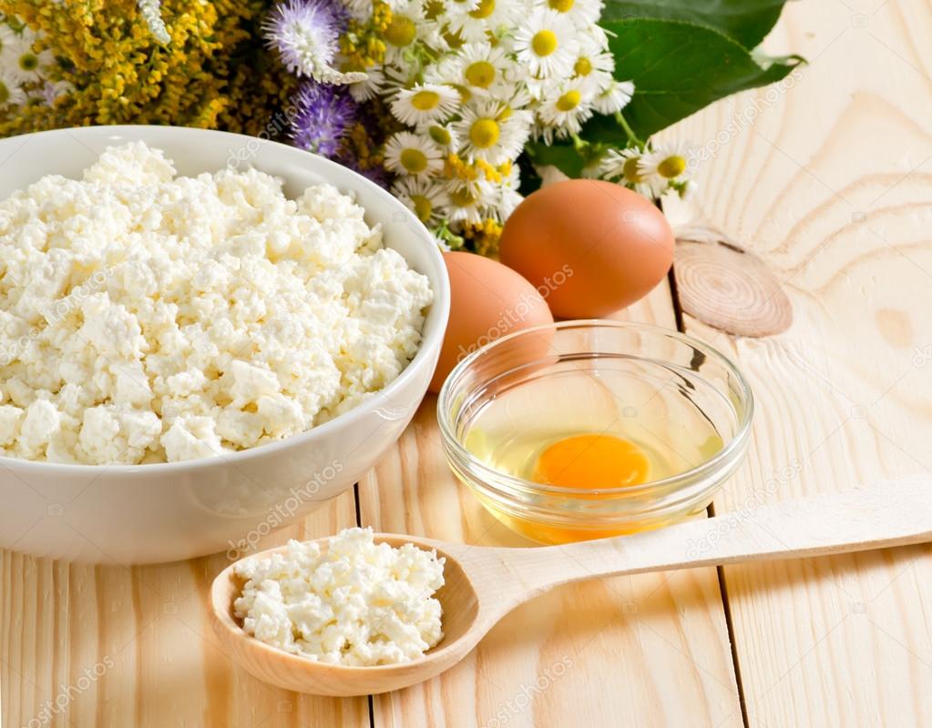 Cottage cheese in bowl with wooden spoon  and eggs