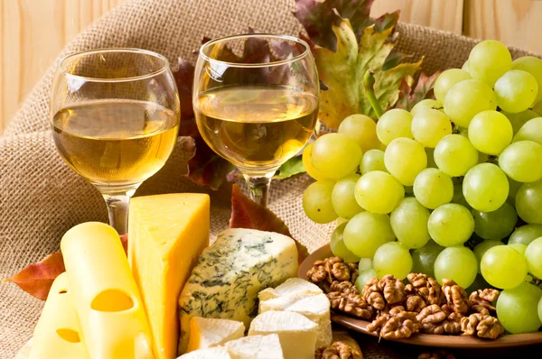 Witte wijn met kaas, walnoten en druiven op zak — Stockfoto