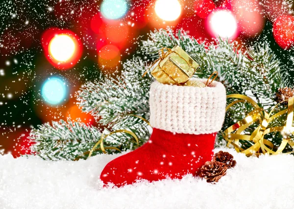 Weihnachtsmannstiefel mit Geschenkbox und Zapfen im Schnee — Stockfoto