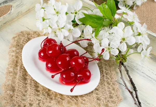 Canned cherries, twig of cherry tree and openwork napkin. — Stock Photo, Image