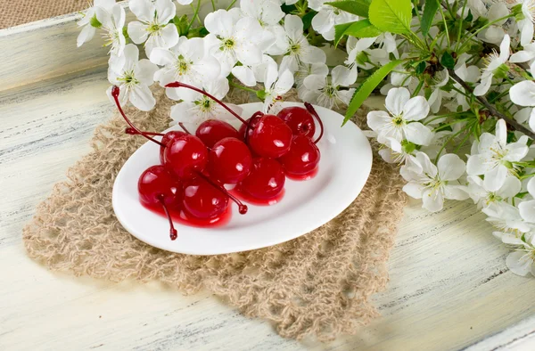 Canned cherries, twig of cherry tree and openwork napkin. — Stock Photo, Image