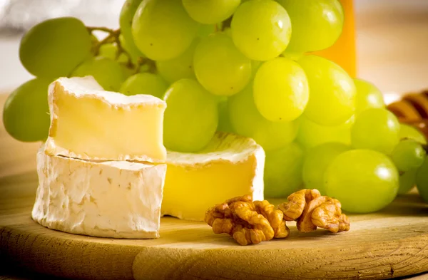 Still life of cheese,  walnuts and grapes — Stock Photo, Image