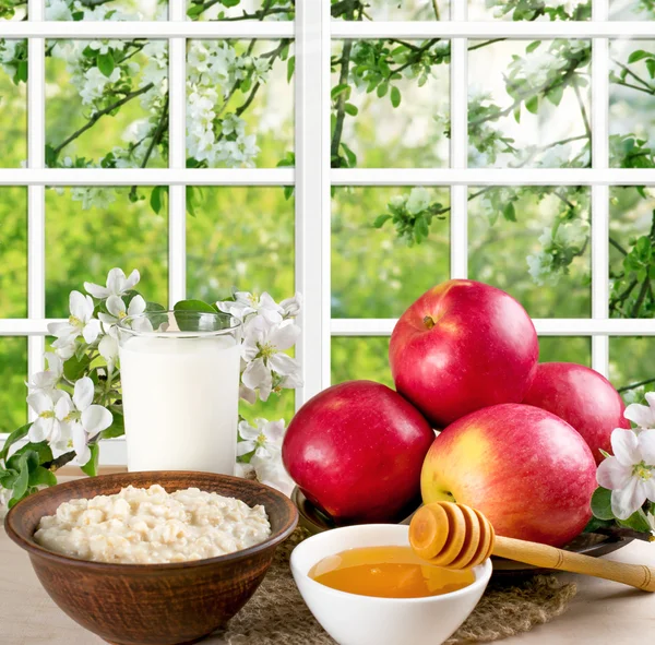 Naturaleza muerta con manzanas, avena, miel, leche y jardín al aire libre —  Fotos de Stock