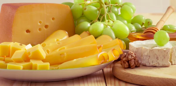 Still life with cheese, walnuts, honey and grapes — 图库照片