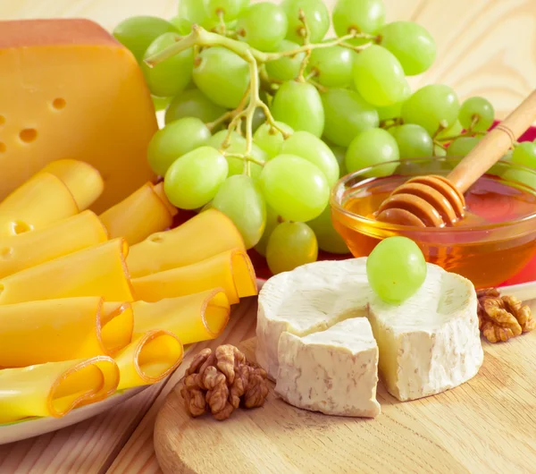 Still life with cheese, walnuts, honey and grapes — 图库照片