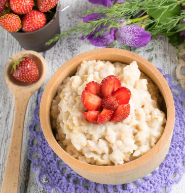 Oatmeal with strawberries in the wooden bowl