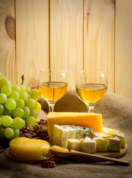 Vino blanco con queso, miel, nueces y uvas sobre saco — Foto de Stock