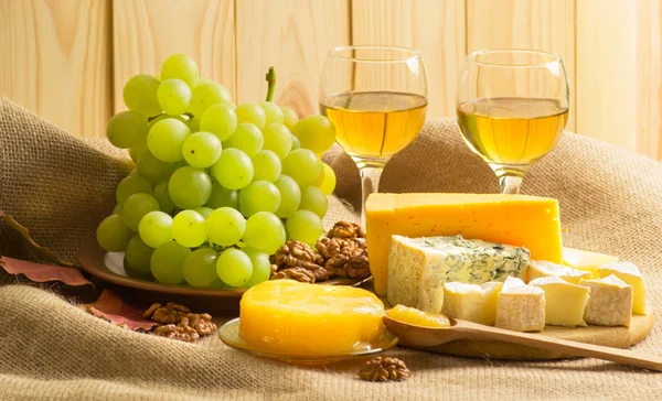 Witte wijn met kaas, honing, walnoten en druiven op zak — Stockfoto