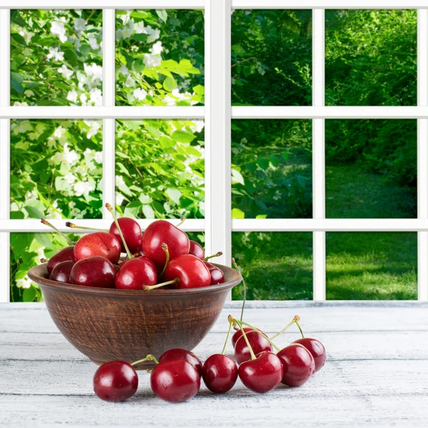 Sweet cherry on the wooden table and garden outside the window — Stock Photo, Image