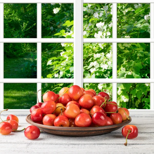Sweet cherry on the wooden table and garden outside the window — Stock Photo, Image