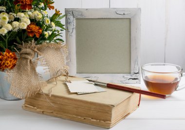 Tagetes çiçek buketi ile fotoğraf çerçevelemek ve eski kitap ile su bardağı te