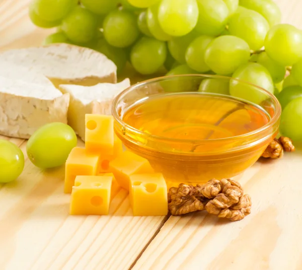 Still life of cheese, honey, walnuts and grapes — Stock Photo, Image