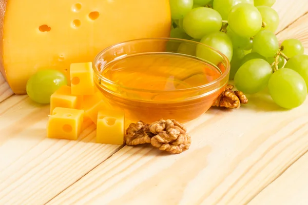 Still life of cheese, honey, walnuts and grapes — Stock Photo, Image