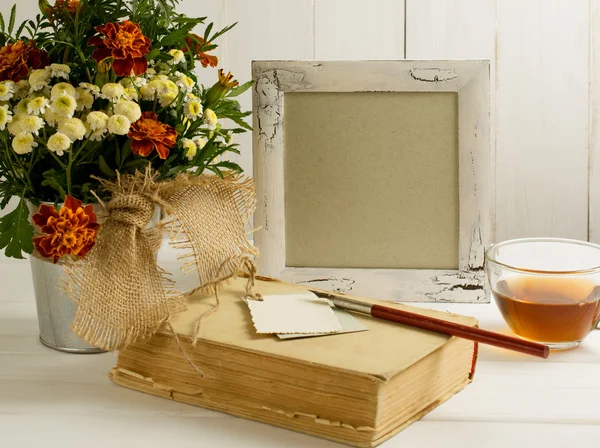 Tagetes buquê de flores com moldura de foto e livro antigo com copo te — Fotografia de Stock
