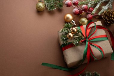 Noel arkaplanı, el yapımı hediye kutusu, fiyonklu, dekoratif köknar dalı, ağaç süsleme topları. Yeni yıl kış tatili kompozisyonu hediye, dekor ve metin için kopya alanı, üst görünüm.