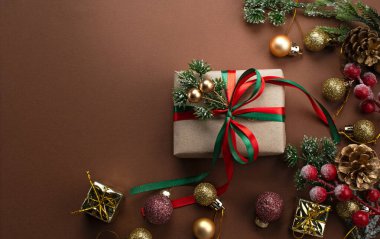 Noel arkaplanı, fiyonklu el yapımı hediye kutusu, ağaç süslemesi için dekoratif köknar dalı, top ve koni. Yeni yıl bayramı süsleri, hediyeler, dekorasyon ve metin için kopya alanı, üst görünüm.