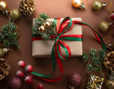 Noel süsleri, fiyonklu el yapımı hediye kutusu, dekoratif köknar dalı, parıldayan toplar ve ağaç süslemeleri için altın koniler. Yeni yıl kış tatili kompozisyonu hediyeler, dekorlar, üst manzara.