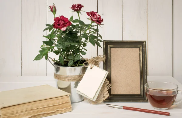 Moldura de foto retro e caneta velha com buquê de rosas na placa de madeira — Fotografia de Stock