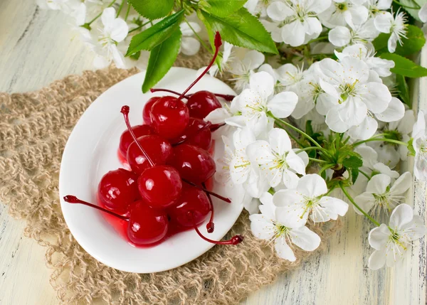 Canned cherries, twig of cherry tree and openwork napkin. — Stock Photo, Image