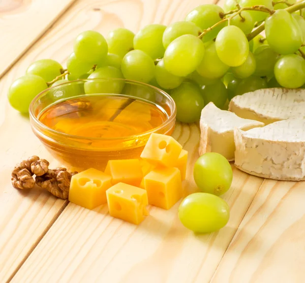 Bodegón de queso, miel, nueces y uvas — Foto de Stock