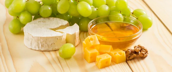 Натюрморт из сыра, меда, грецких орехов и винограда — стоковое фото