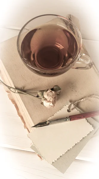 Old book with decorative  card, dried roses, nib pen and cup tea — Stock Photo, Image