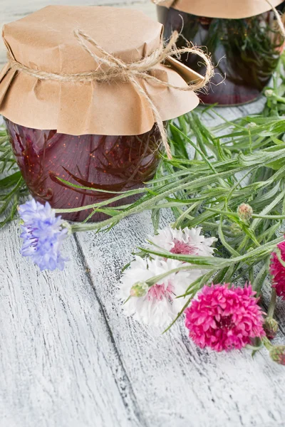 Ingeblikte aardbeienjam en boeket van korenbloemen — Stockfoto