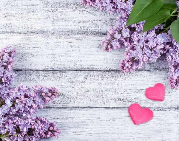 Lilac flowers and hearts on wooden planks — Stock Photo, Image