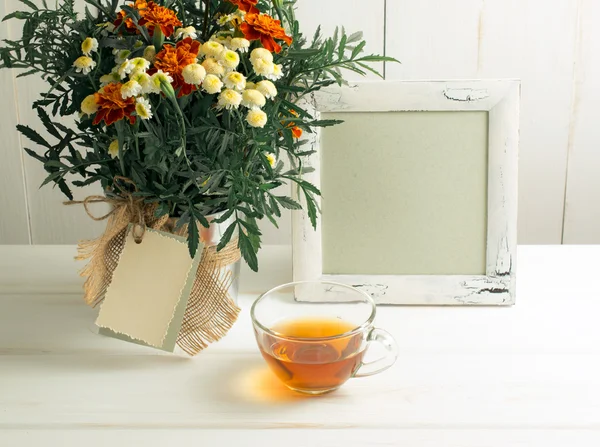 Tagetes buquê de flores com moldura de fotos e xícara de chá — Fotografia de Stock