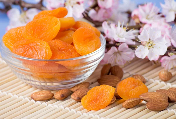Dried apricots with almonds and blossoming branch — Stock Photo, Image