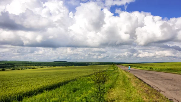 Alone man on country road viewing in wheat field with clouds sto — Stock Photo, Image