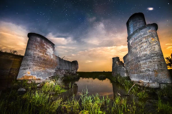 Viejas ruinas de la pared del castillo de noche en los reflejos del lago con estrellas cielo a — Foto de Stock