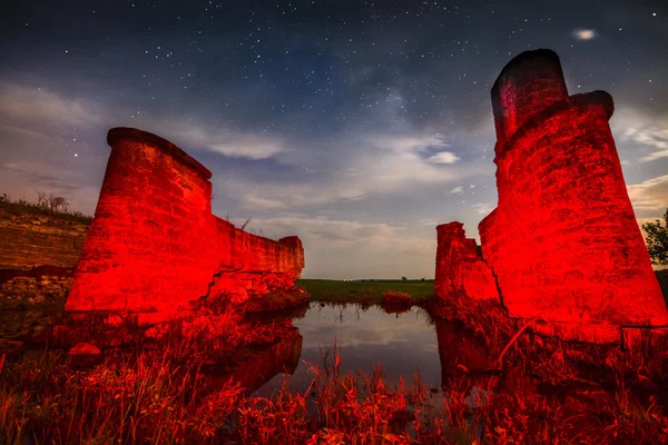 Viejas ruinas de la pared del castillo de noche en los reflejos del lago con estrellas cielo a — Foto de Stock