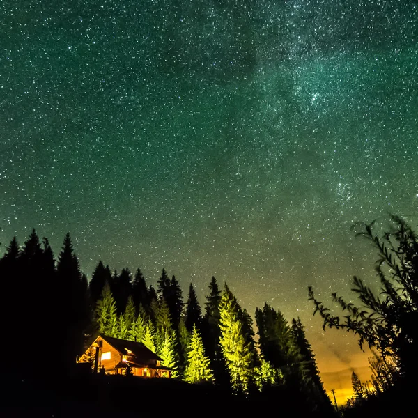 Casa solitaria en luces nocturnas con estrellas, cielo profundo y vía láctea o Fotos de stock libres de derechos