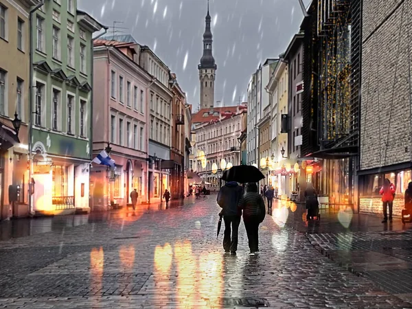 Rainy Autumn street ,people walk with umbrellas evening light blurred on houses and wet pavement in Old Town Of Tallinn travel to Estonia — Stock Image Rainy Autumn Street People Walk Umbrellas Evening Light Blurred Houses Stock Picture