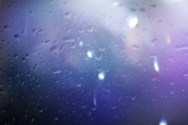 Pencereye düşen yağmurlu su damlaları bulanık mavi ışık yansıma yağmuru desenli arka plan hava durumu 