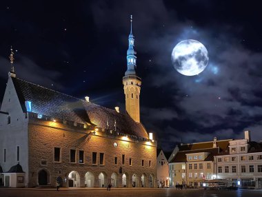 Tallinn eski belediye binası meydanında gece ışığında yansıyan su birikintilerinde yıldızlı bir gecede Estonya 'ya ortaçağ şehir seyahati  