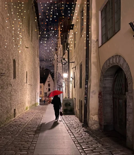 Night Street Rain weather women walk with red umbrella on Medieval Old town of Tallinn night blurred light and Christmas decoration travel To Estonia
