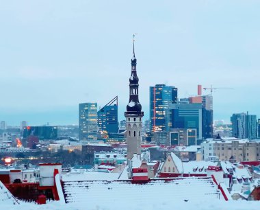 Tallinn 'in eski panorama kasabasında kar yağışlı ortaçağ şehir çatı evi ve Estonya' daki belediye binasında kar taneleri düşüyor. 