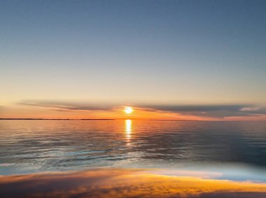   Deniz batımında güzel bir gün batımı pembe altın sarısı bulutlar üzerinde mavi mavi gökyüzü yarı akşam, su dalgası doğa manzarası yansıması