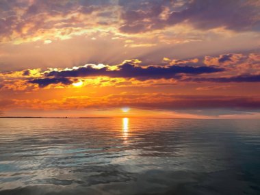   Deniz batımında güzel bir gün batımı pembe altın sarısı bulutlar üzerinde mavi mavi gökyüzü yarı akşam, su dalgası doğa manzarası yansıması