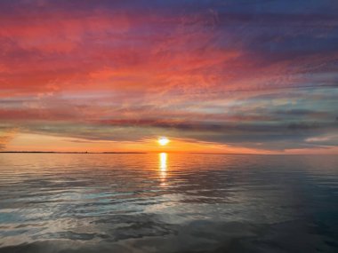 Akşam portakal rengi gün batımı deniz dramatik bulutları pembe altın sarısı gökyüzü yazın mavi, su dalgası doğa manzarası yansıması