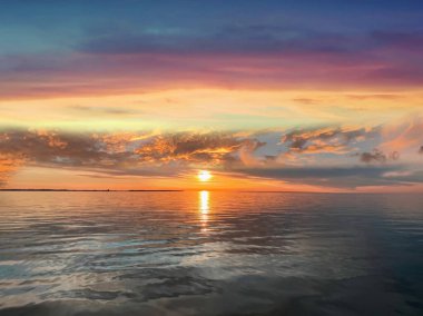   Deniz batımında güzel bir gün batımı pembe altın sarısı bulutlar üzerinde mavi mavi gökyüzü yarı akşam, su dalgası doğa manzarası yansıması