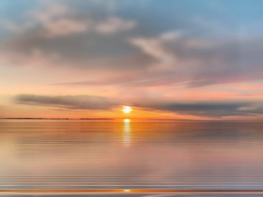   Deniz batımında güzel bir gün batımı pembe altın sarısı bulutlar üzerinde mavi mavi gökyüzü yarı akşam, su dalgası doğa manzarası yansıması