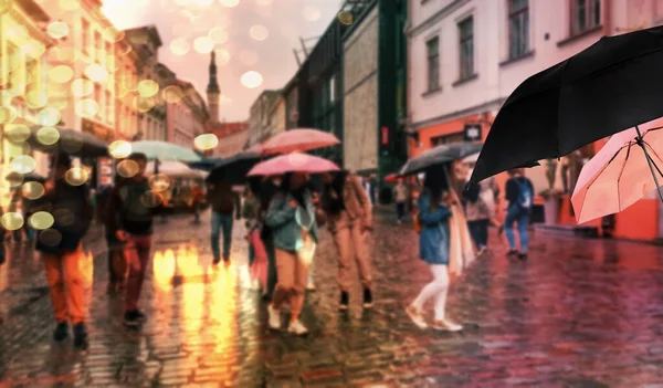 rainy season wet street people under rain with umbrella in Tallinn old town Estonia