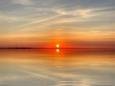 Altın turuncu gün batımı dramatik gökyüzü eflatun pembe deniz suyu güneş ışığı akşam deniz manzarası yansıması 