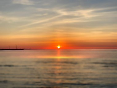 Altın turuncu gün batımı dramatik gökyüzü eflatun pembe deniz suyu güneş ışığı akşam deniz manzarası yansıması 