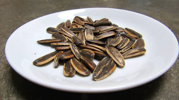 Close Up of Sunflower Seeds on a White Plate. Suitable for organic food-themed content.