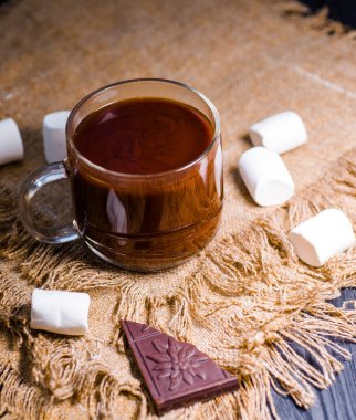 Marşmelovlu bir fincan sıcak çikolata ve bir kalıp koyu çikolata.