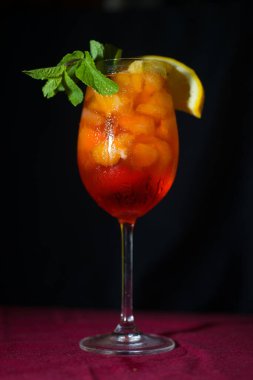 Koyu bir ortamda, içinde likör ve likör bulunan cam aperol kokteyli.